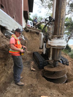 Workers executing typical process for drilling caissons (pilings) used in the foundation of hillside homes