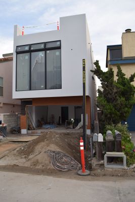 Construction site o 3-story house with new stucco surface, roof deck and garage area without door or deck railing
