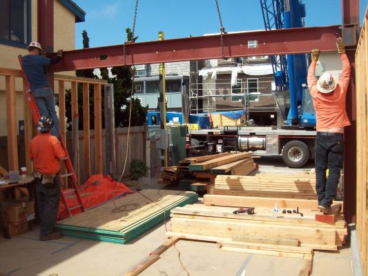 Steel moment frame being installed on new home foundation by a cre of three men