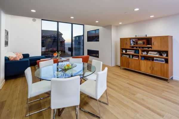Large dining & lving room with round table and custome cabinet near a fire place with ocean view
